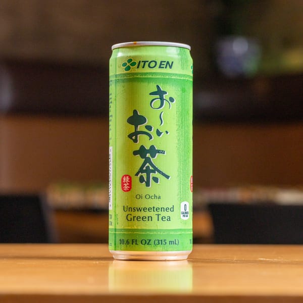 A green can of Ito En Oi Ocha Unsweetened Green Tea on a wooden table.