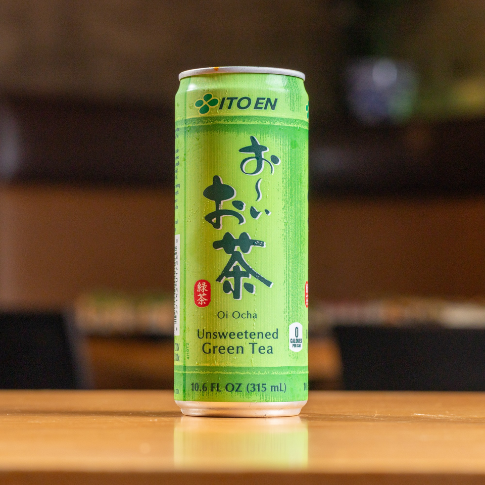 A green can of Ito En Oi Ocha Unsweetened Green Tea on a wooden table.